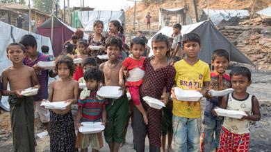 Children are seen taking food which supplied by NGOs and social organization, after a fire at a refugee camp in Ukhia, in the southeastern Cox's Bazar district on March 24, 2021.